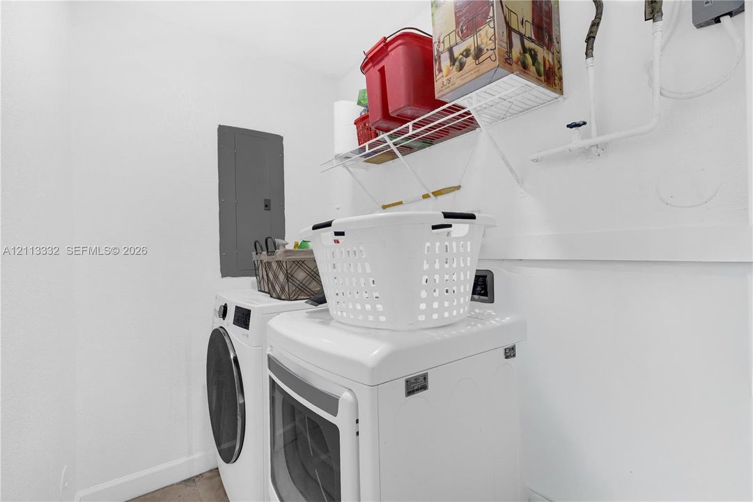 Dedicated laundry area featuring white walls, wire shelving, and an electrical service panel
