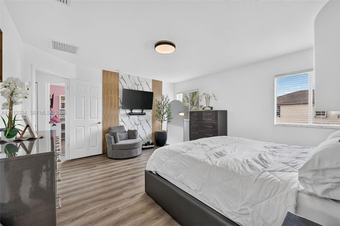 Room featuring wood-finish flooring, accent wall with stone-patterned slab and vertical wood slats, and flush-mount circular lighting