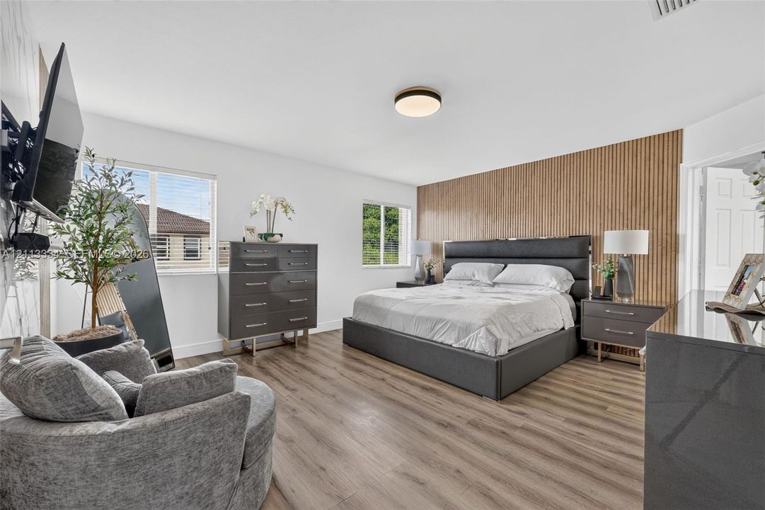 Wood-finish flooring, vertical wood-slat accent wall, and flush-mount ceiling lighting