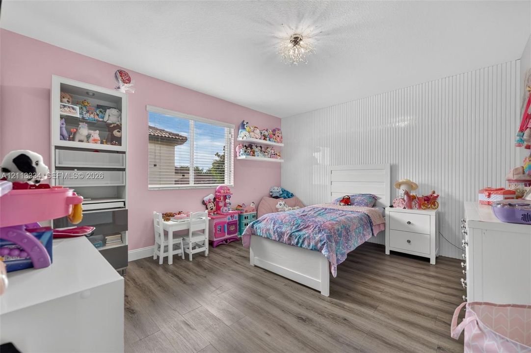 Wood-finish flooring, vertical slat wall paneling, built-in recessed shelving unit, and a ceiling-mounted crystal-style light fixture