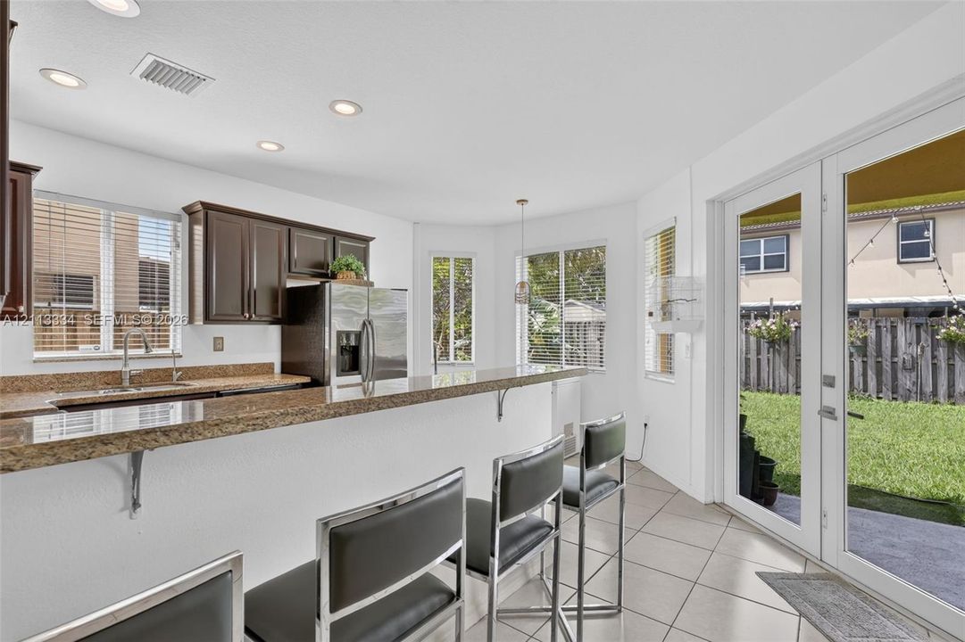 Kitchen featuring stone countertops, dark wood cabinetry, recessed lighting, tile flooring, and glass-paneled double doors providing rear exterior access