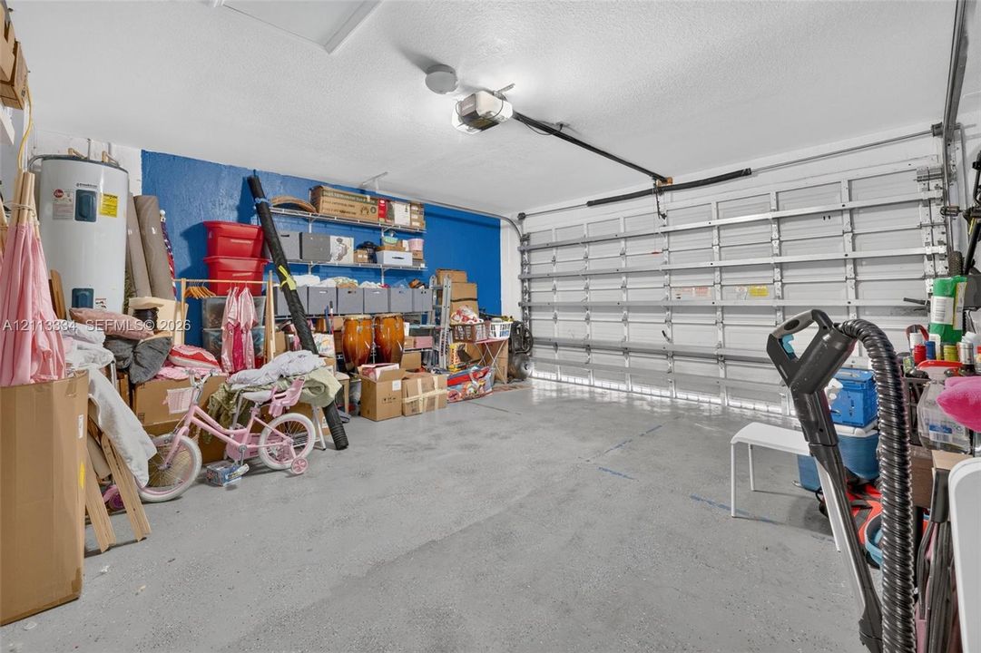 Two-car garage featuring a sectional overhead door, automated door opener, wall-mounted storage shelving, and a water heater