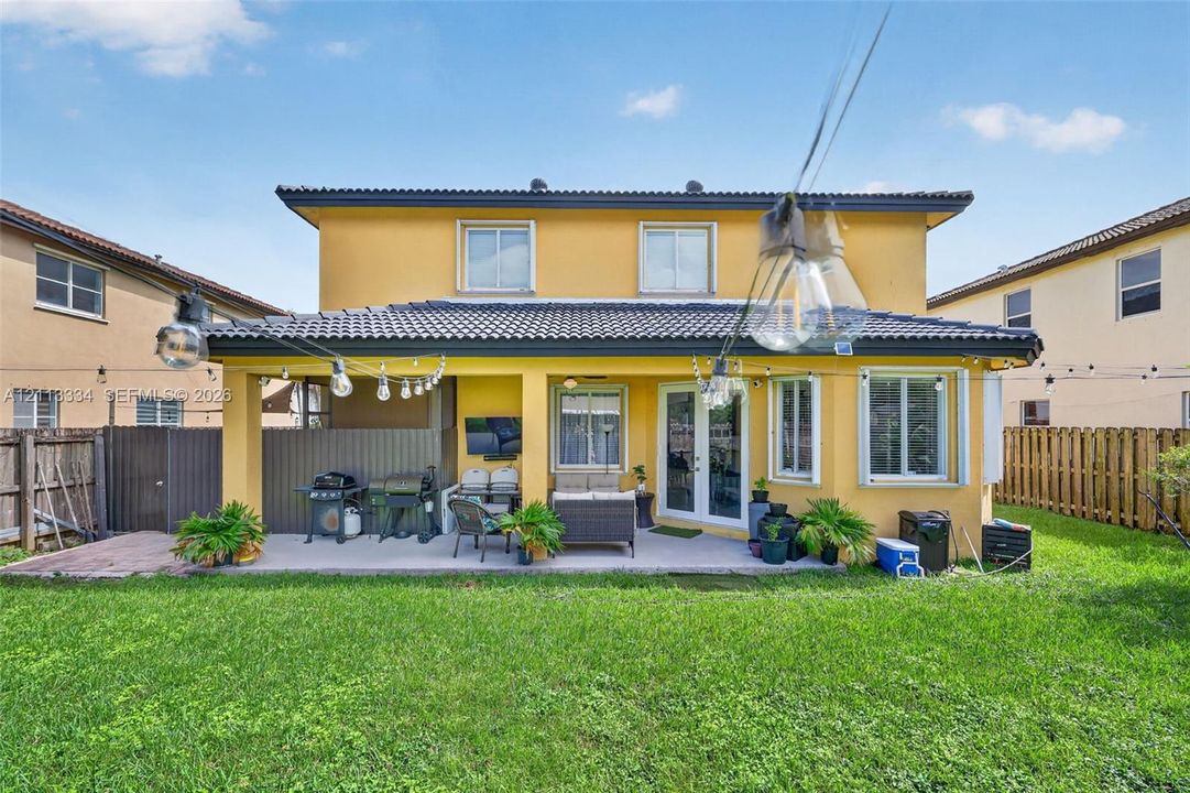 Rear exterior featuring a covered patio, tile roof, and enclosed backyard with wood-style fencing