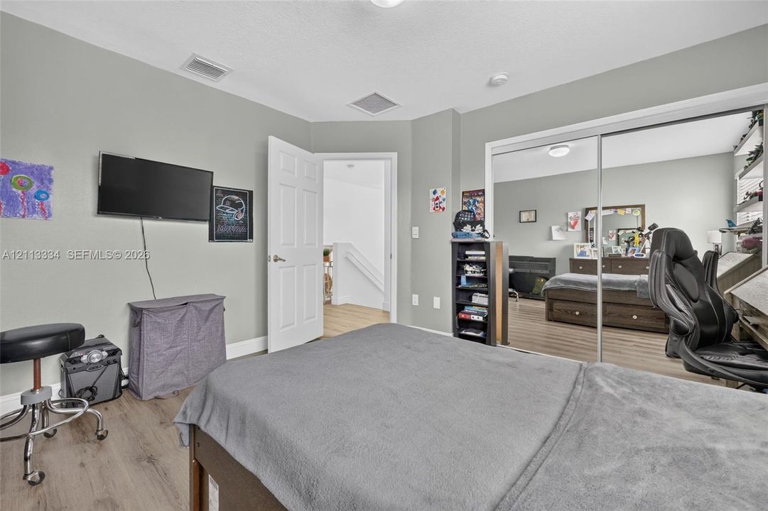 Room interior featuring wood-finish flooring, a double-panel sliding mirrored closet door, and a multi-panel interior swing door