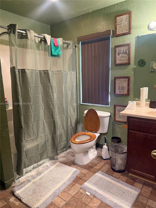 Bathroom featuring a shower-tub combination, wall-mounted vanity with a solid-surface countertop, and ceramic tile flooring