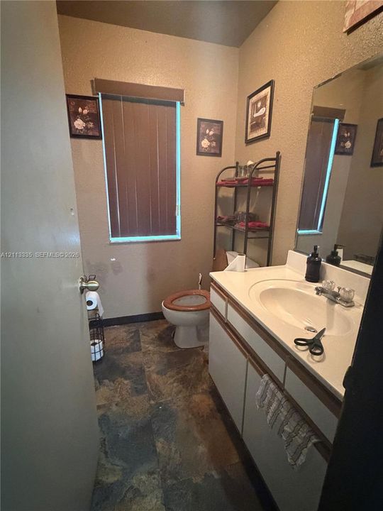 Bathroom featuring a vanity with an integrated sink, neutral-toned cabinetry, a large wall-mounted mirror, and stone-finish flooring
