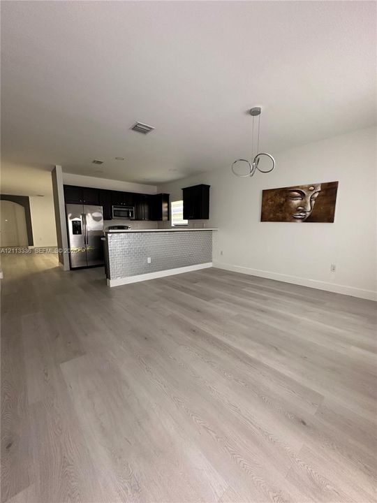Kitchen area featuring dark cabinetry, stainless steel appliances, a metallic textured breakfast bar, and wood-finish flooring