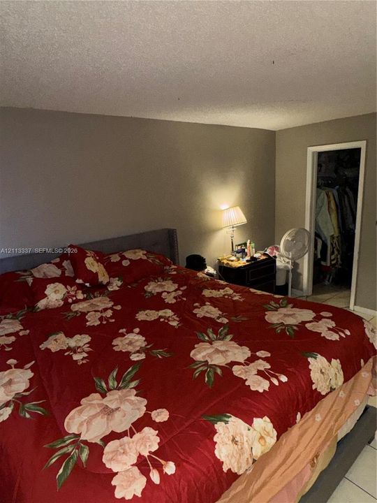 Room featuring neutral wall paint, tiled flooring, and a walk-in closet with built-in shelving