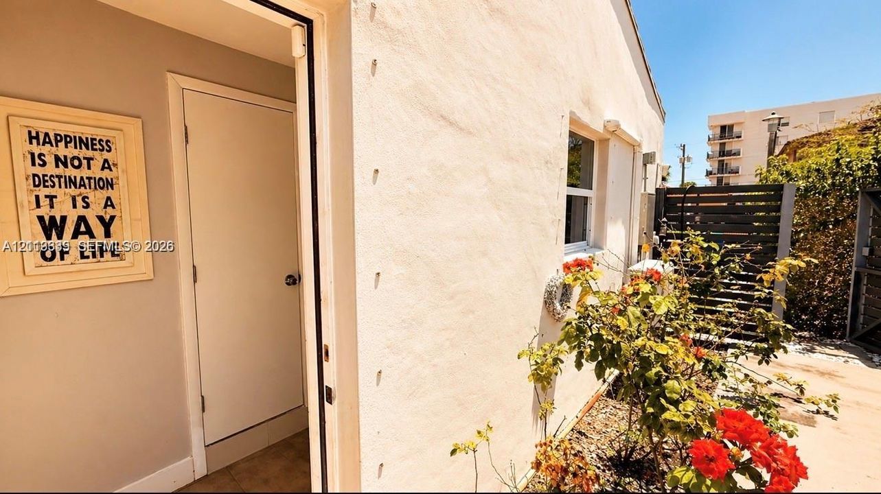 Stucco exterior featuring a white door, single-pane window, and horizontal slatted privacy fencing