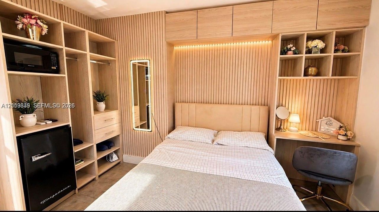 Custom light-toned wood-finish built-in cabinetry featuring open shelving, integrated desk, and vertical slat accent wall paneling with recessed ambient lighting