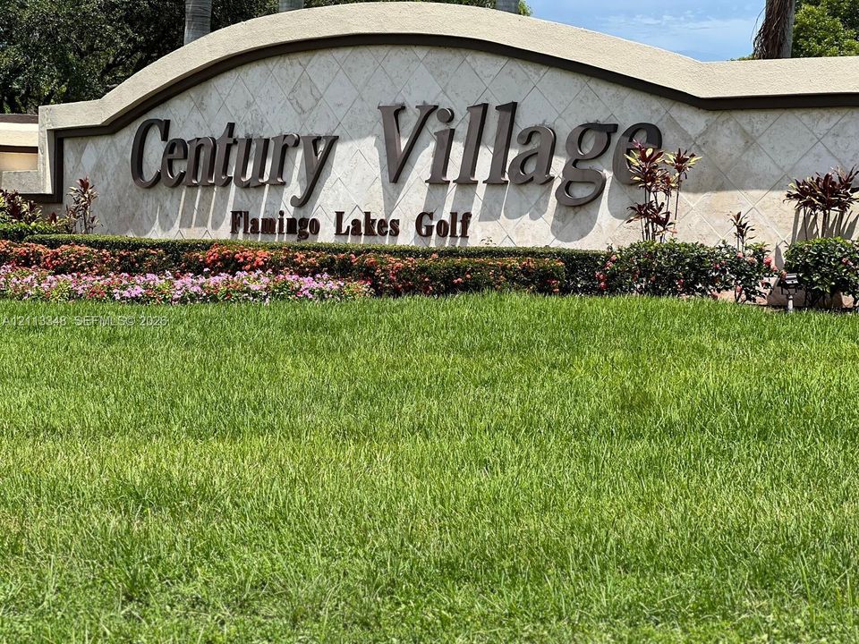 Community entrance monument featuring a stone-faced wall, dimensional lettering, and integrated landscaping with manicured lawn and ornamental shrubbery