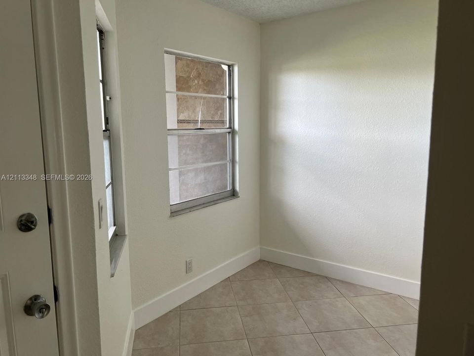 Neutral-toned ceramic tile flooring, crisp white walls, and dual sliding windows with metallic frames