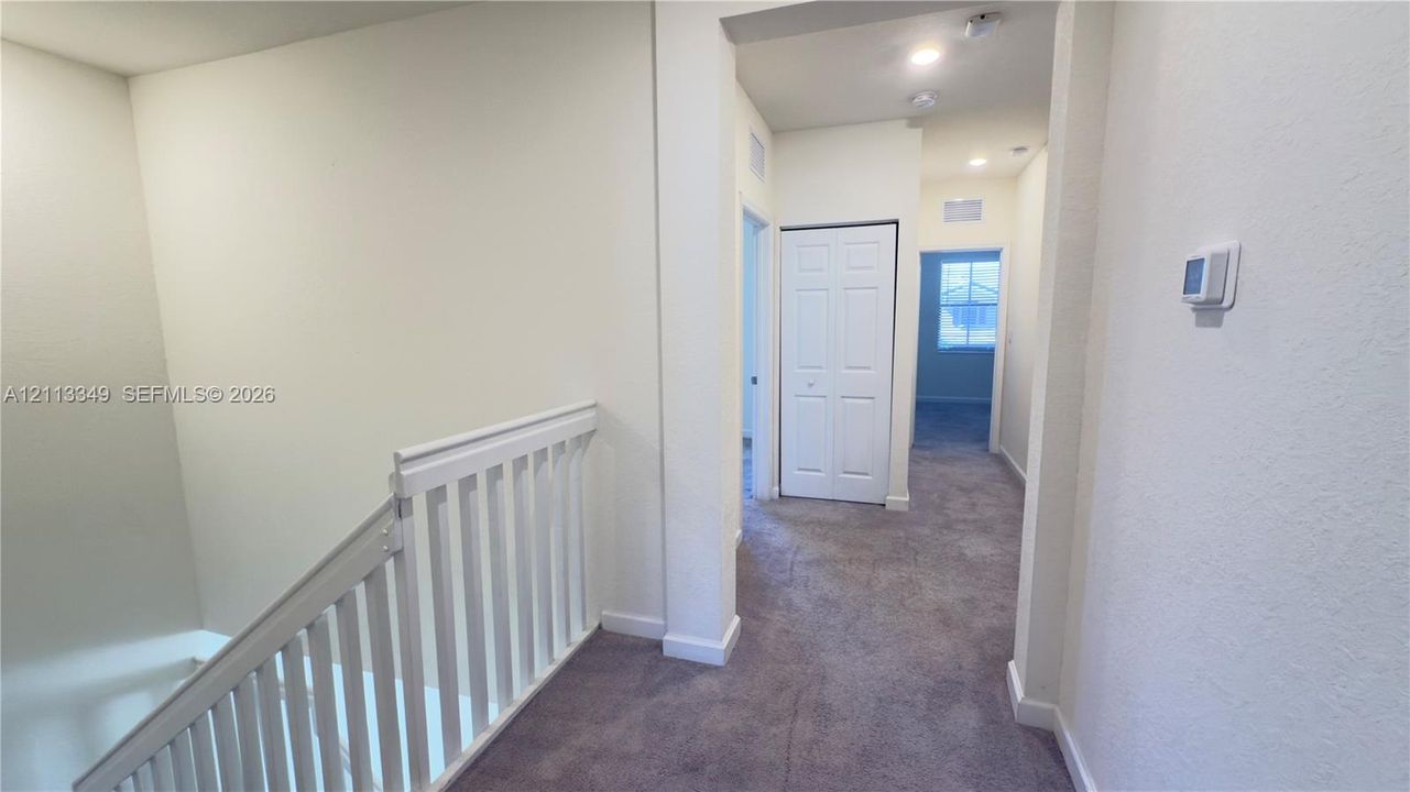 Neutral wall finish, carpeted flooring, white wooden stair railing, and dual-panel closet door
