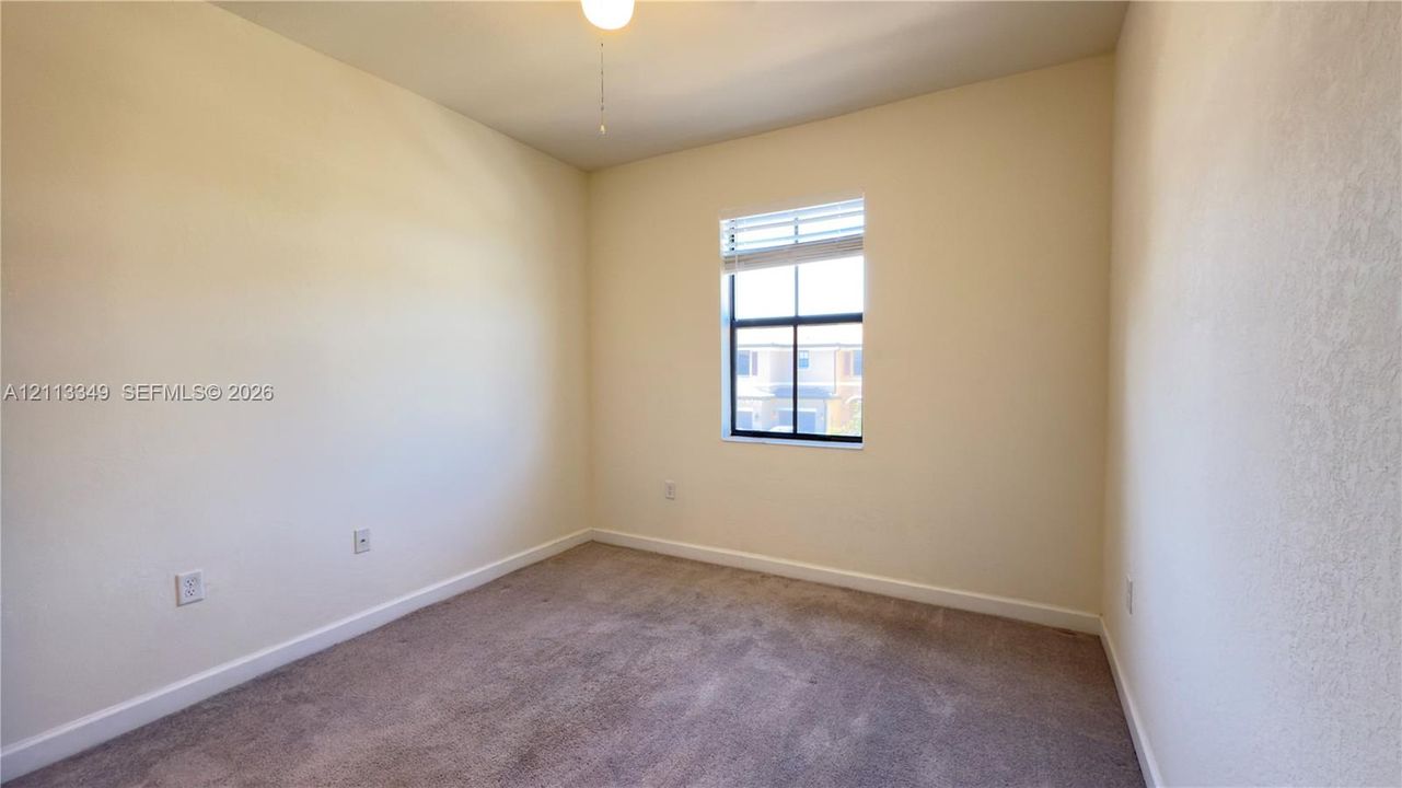 Room featuring neutral wall finishes, plush wall-to-wall carpeting, a single-pane window with integrated blinds, and a central ceiling fan fixture