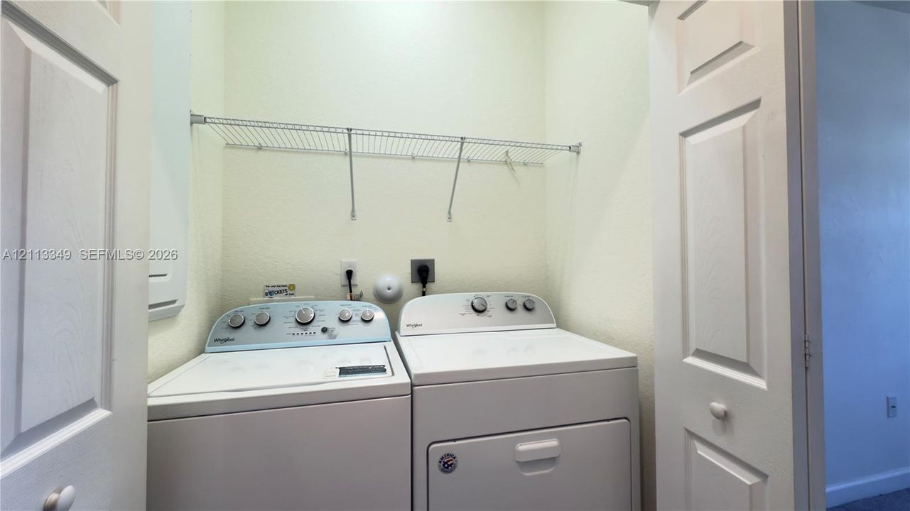 Dedicated laundry area featuring white bi-fold doors and integrated wire shelving