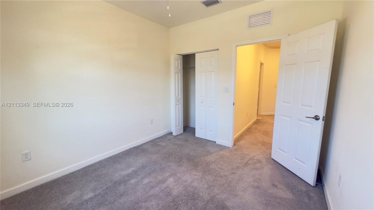 Neutral-toned interior space featuring neutral wall paint, wall-to-wall carpeting, and white interior doors, including a double-panel closet door