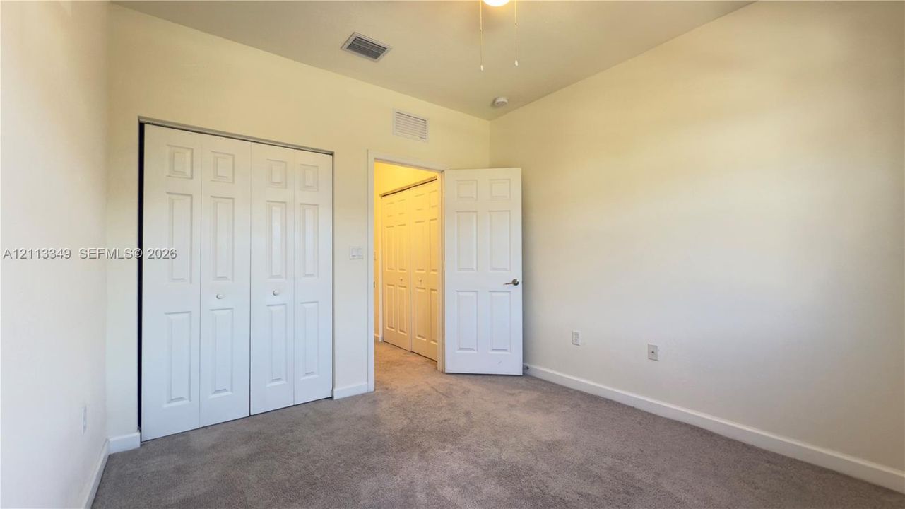 Neutral-toned interior featuring wall-to-wall carpeting, white bi-fold closet doors, a classic six-panel interior door, and a ceiling-mounted light fixture