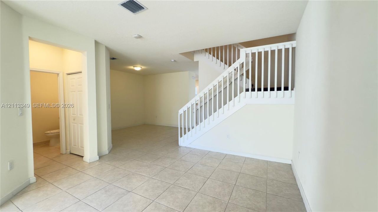Open floor plan featuring tile flooring, a staircase with white balusters, and recessed ceiling lighting