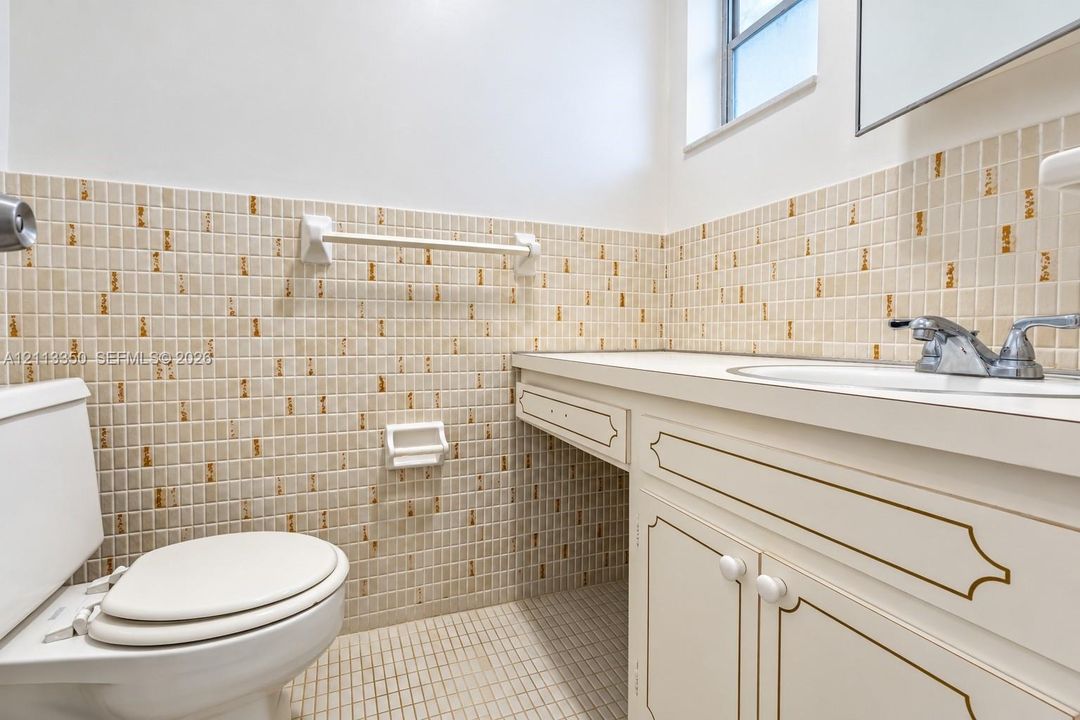 Bathroom featuring a vanity with white cabinetry and decorative trim, a solid surface countertop with an integrated basin, and mosaic tile wall accents