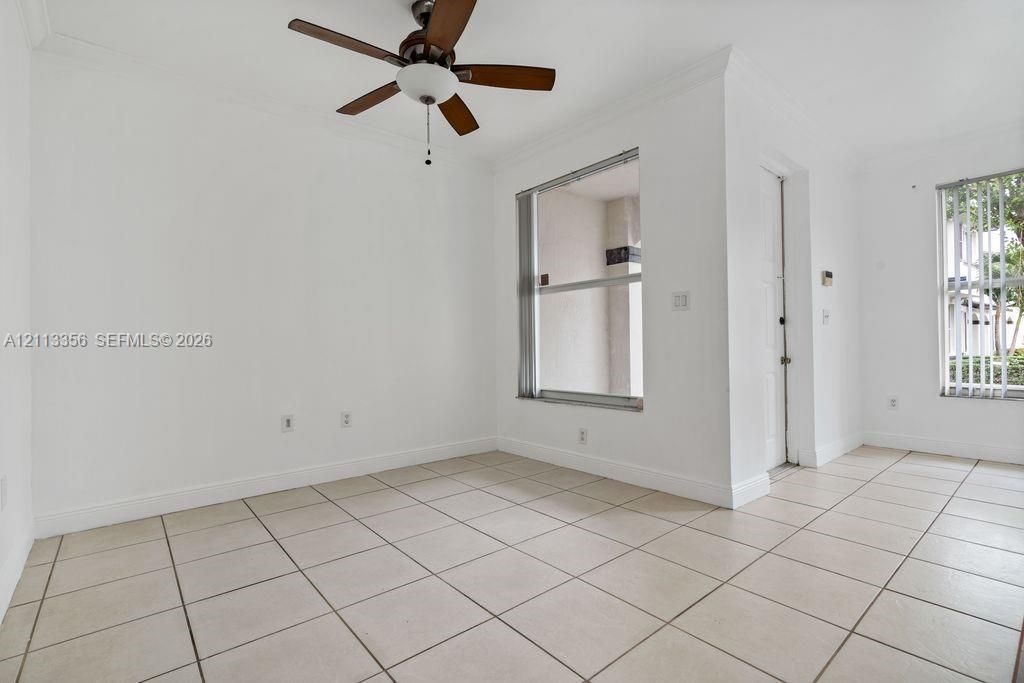 Neutral-toned ceramic tile flooring, ceiling fan with integrated lighting, and multiple windows with vertical blinds
