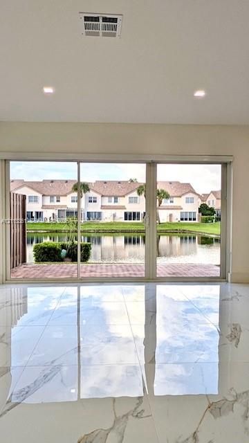 Large-format gloss tile flooring featuring veining throughout, complemented by expansive floor-to-ceiling sliding glass doors and recessed ceiling lighting