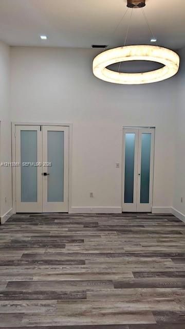 High-ceiling interior featuring wood-finish flooring, a contemporary circular pendant light, and double doors with frosted glass panels