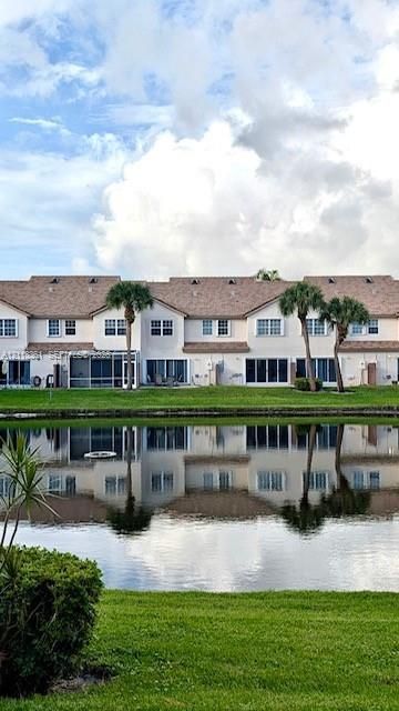 Multi-story exterior featuring multi-pane windows, a shingled roof, screened-in patio, and direct water frontage on a lake