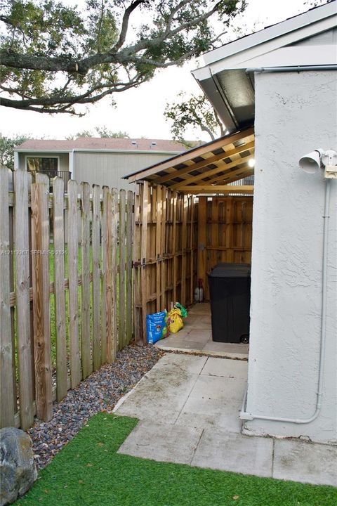 Exterior storage area featuring a wood-slat roof structure, concrete pad, and wood perimeter fencing