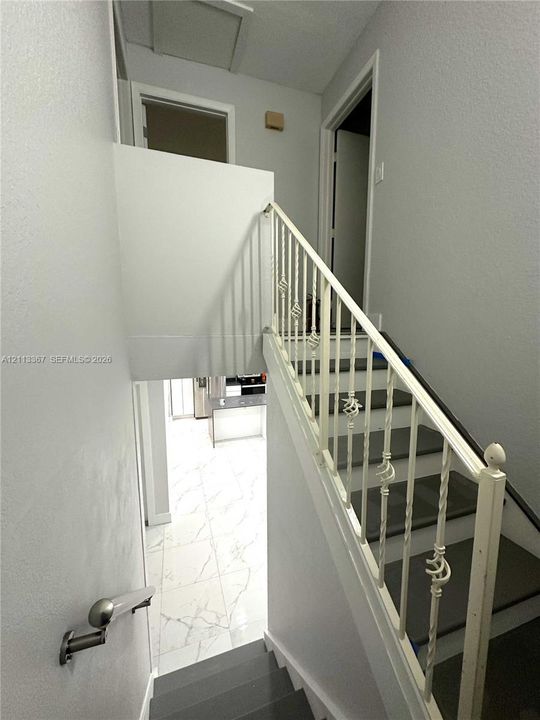 Staircase featuring dark-toned treads, decorative white metal balustrades, and a wall-mounted handrail