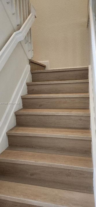 Staircase featuring wood-finish treads and white painted handrails