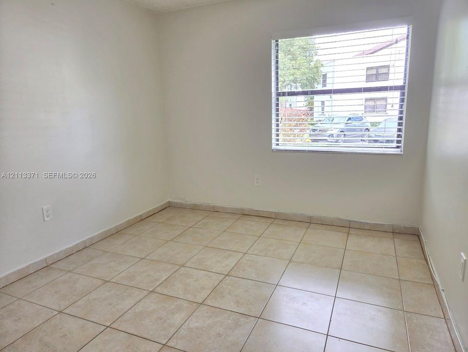 Neutral-toned ceramic tile flooring, clean painted walls, and a large window featuring horizontal blinds