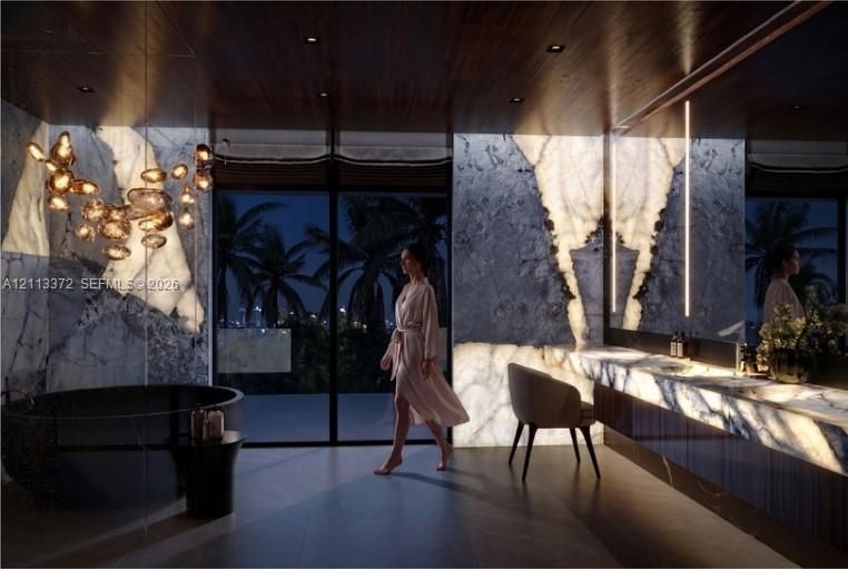 Backlit stone wall cladding, floor-to-ceiling glass sliding doors, dark wood-finish ceiling, freestanding circular soaking tub, and built-in stone vanity with integrated lighting