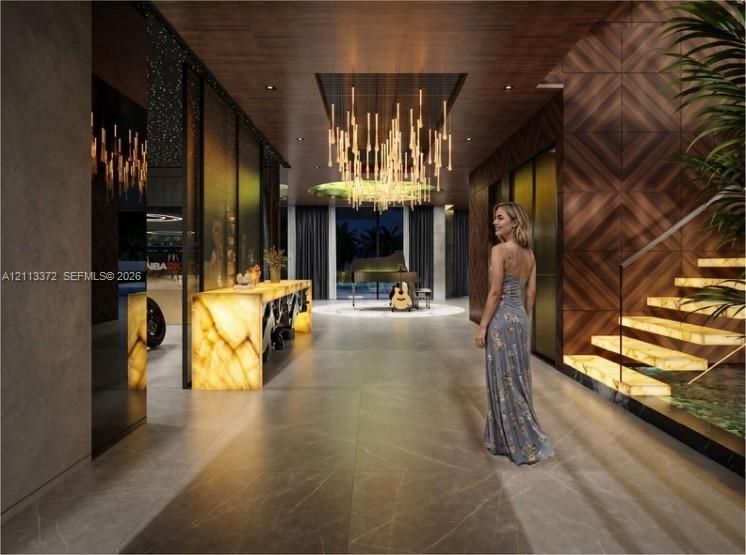 Foyer featuring large-format stone-finish floor tile, geometric wood-paneled walls, custom illuminated stone console, tiered linear chandelier, and floating staircase with backlit treads