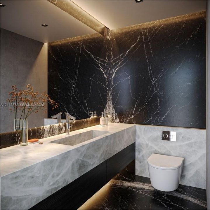 Floating vanity with integrated sink, dark-veined stone wall cladding, wall-mounted dual-flush toilet, recessed LED accent lighting, and polished stone countertops