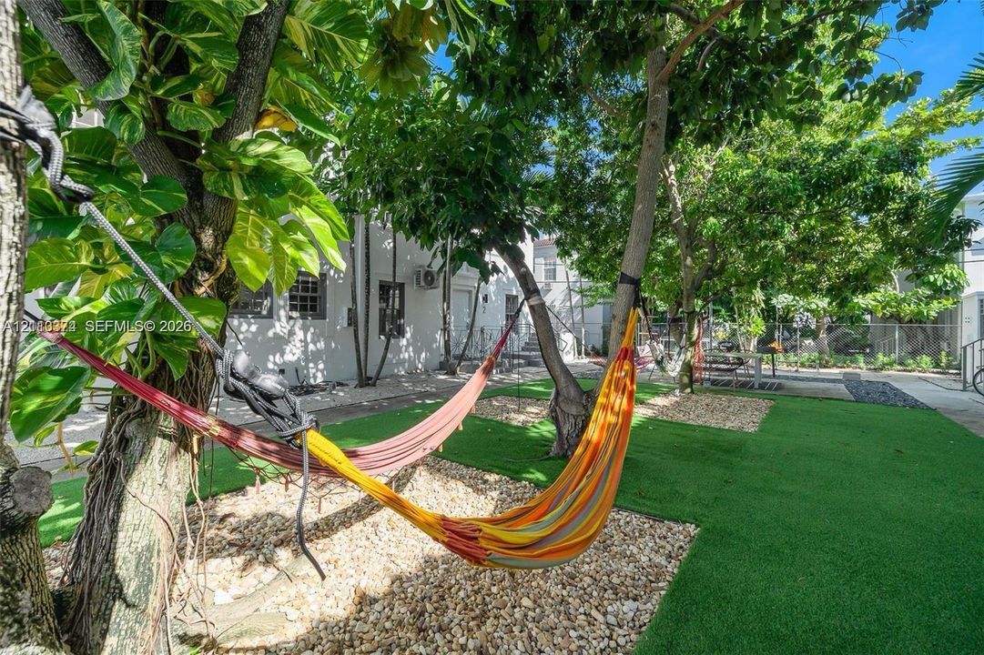Outdoor space featuring artificial turf, decorative stone landscaping, and mature trees