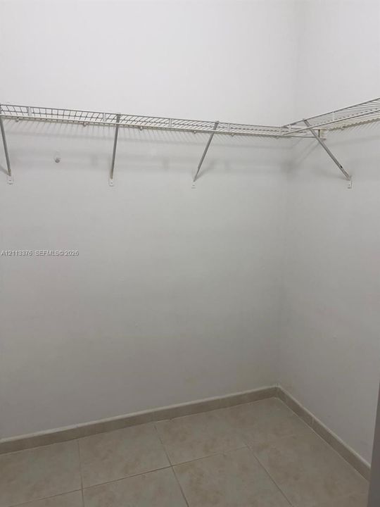Storage area featuring white walls, ceramic tile flooring, and metal wire shelving