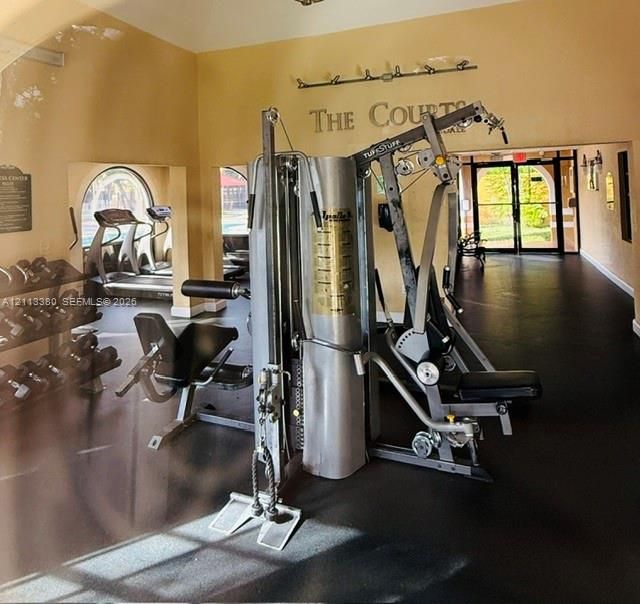 Fitness center featuring rubber flooring, arched windows, and mounted lighting fixtures