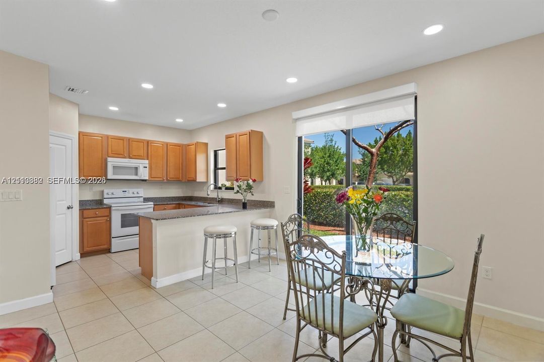 Kitchen featuring wood cabinetry, stone-finish countertops, recessed lighting, tile flooring, and a sliding glass door