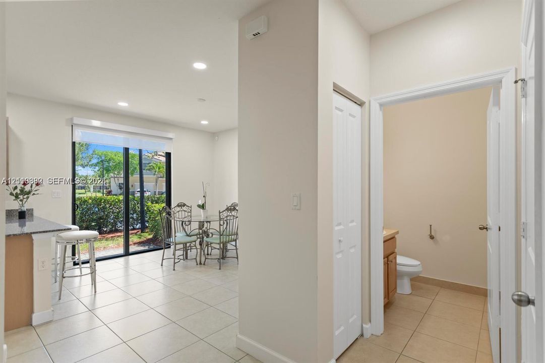 Ceramic tile flooring, recessed lighting, breakfast bar with stone-surface countertop, floor-to-ceiling glass sliding doors, and bi-fold closet doors