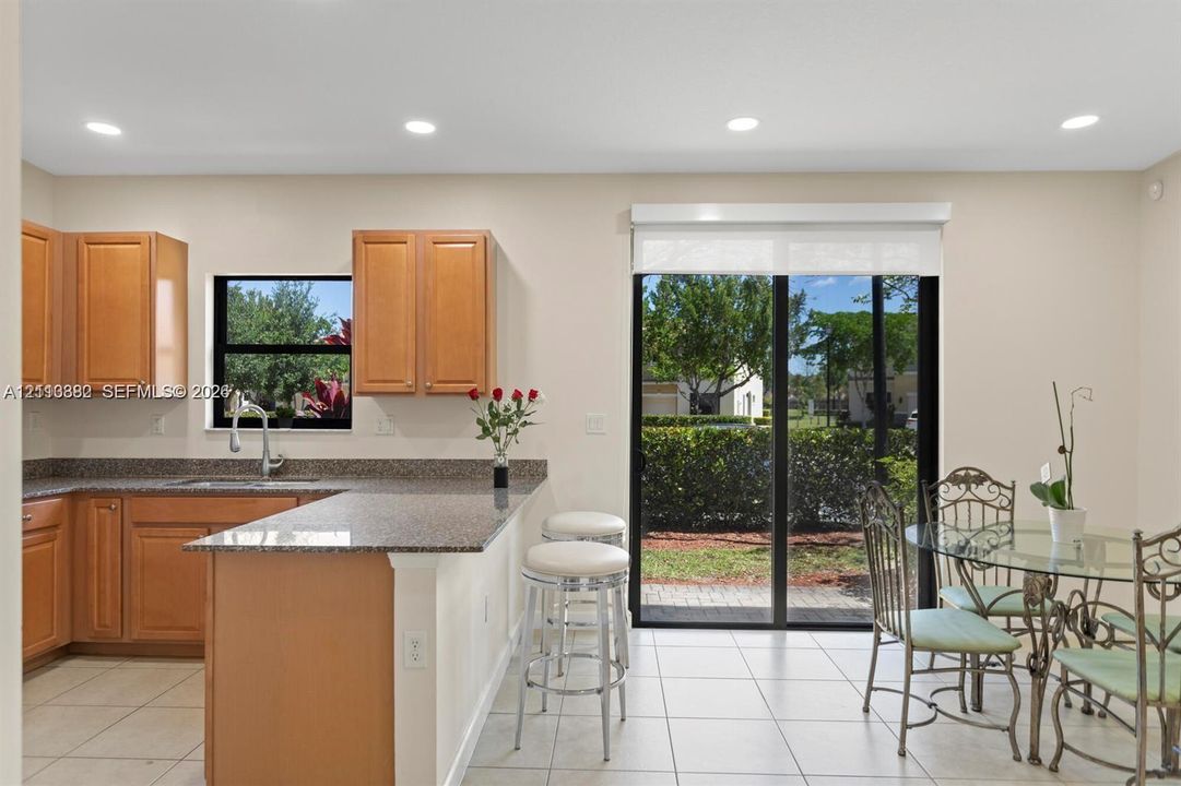 Kitchen featuring light wood-finish cabinetry, stone-surface countertops, recessed lighting, and sliding glass doors with exterior access