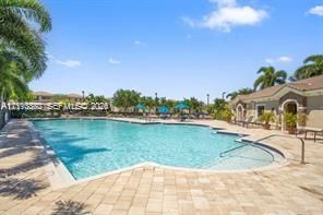 Swimming pool with a paved deck, stepped entry, and palm tree landscaping