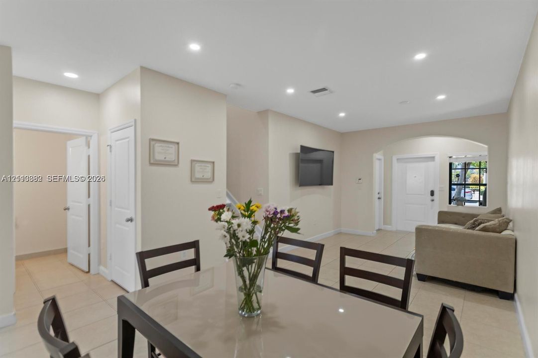 Open-concept area featuring neutral wall paint, tile flooring, recessed ceiling lighting, and an arched entryway