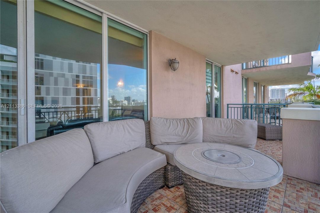 Covered balcony featuring floor-to-ceiling glass sliding doors, stone-tiled flooring, and metal railing