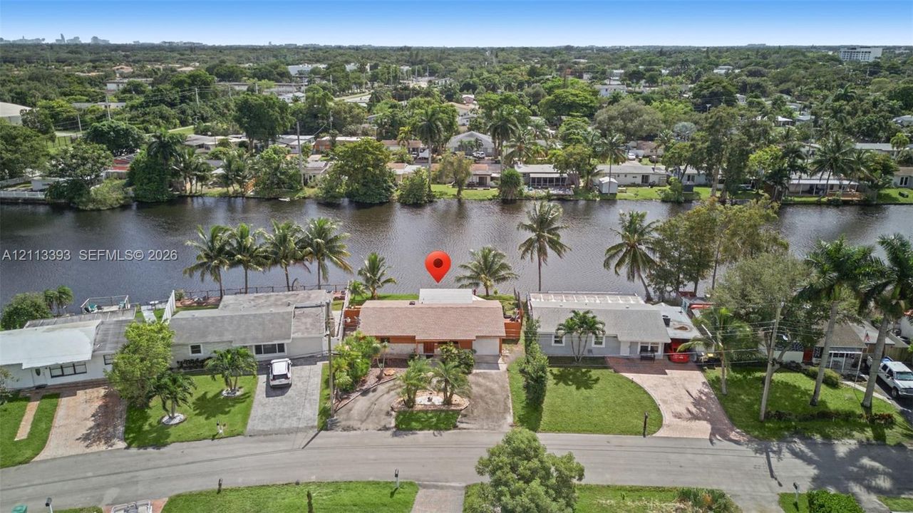 Waterfront property featuring direct water frontage, concrete bulkhead, mature palm trees, and residential street access