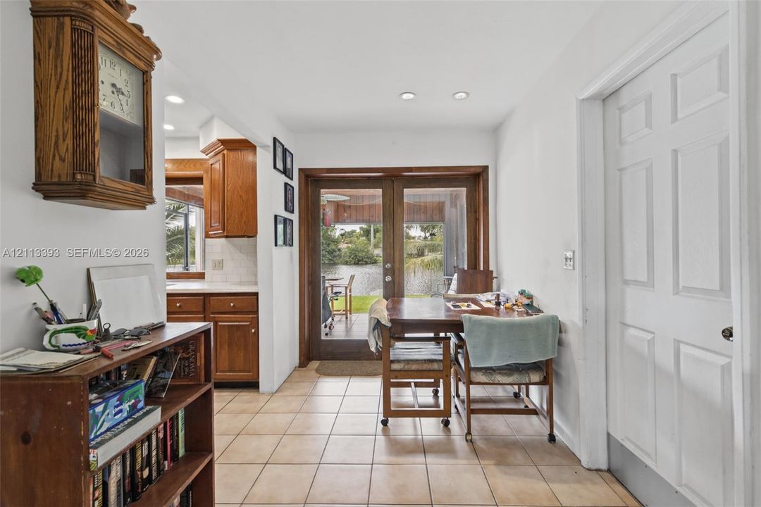 Ceramic tile flooring, wood-framed French doors, and recessed lighting, with wood cabinetry visible in the background