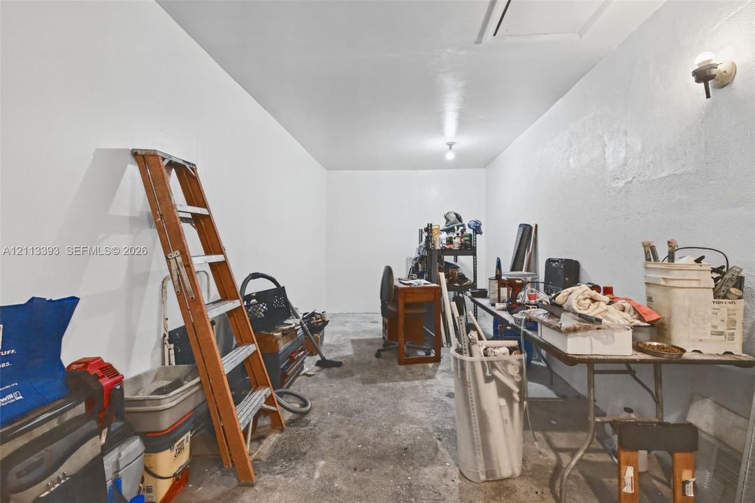 Enclosed storage area featuring white painted walls, a concrete floor, and dual wall-mounted light fixtures