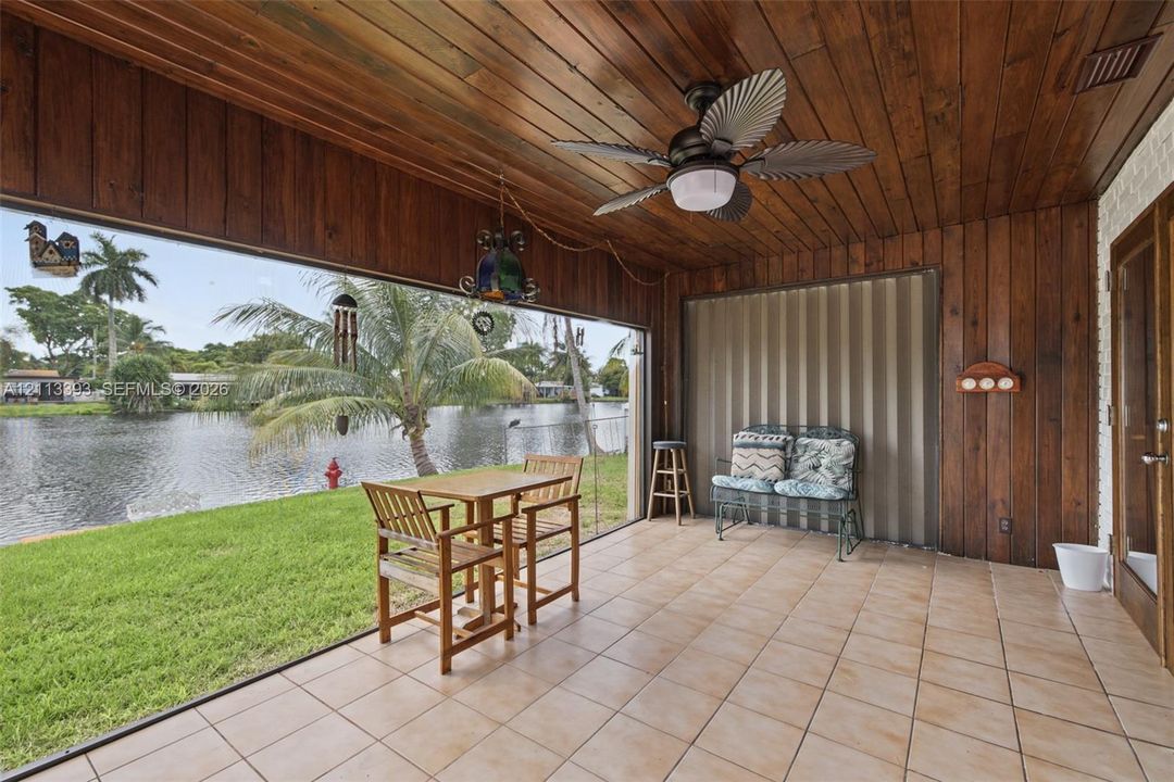 Screened patio featuring wood-paneled walls and ceiling, ceramic tile flooring, and a ceiling fan