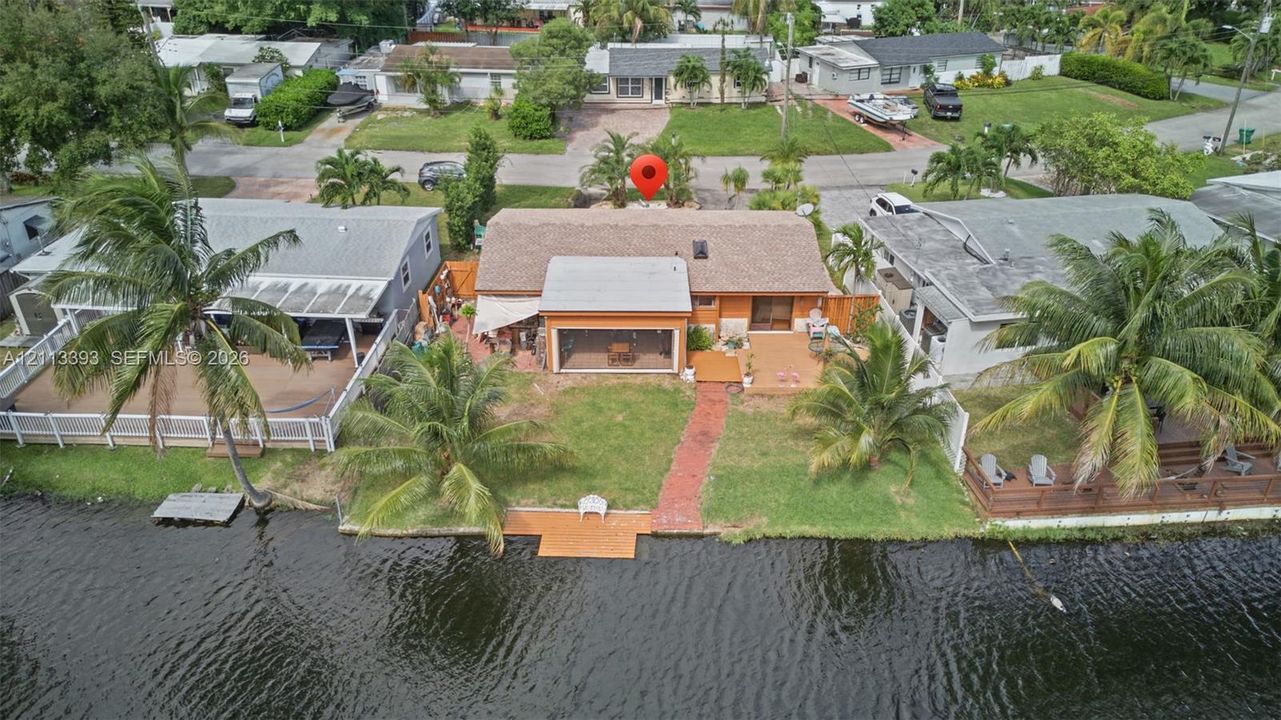 Waterfront property featuring a private dock, screened-in porch, brick-paver walkway, and mature palms