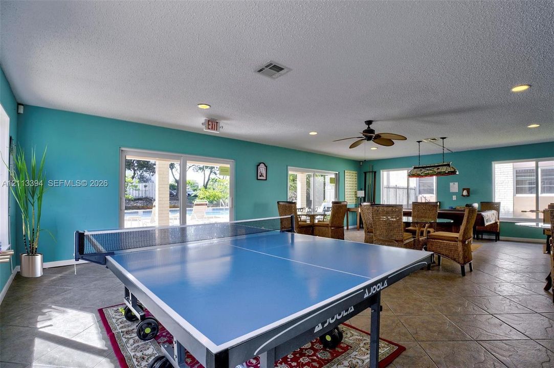 Spacious interior featuring large-format tile flooring, recessed lighting, multiple sets of sliding glass doors, and a ceiling fan