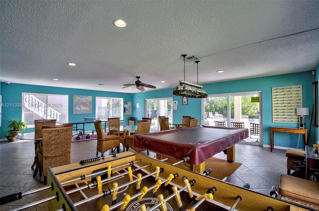 Spacious recreation room featuring neutral tile flooring, recessed lighting, ceiling fan, and sliding glass doors